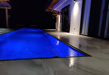 Contemporary zero edge pool with blue lighting in a Manhattan Beach backyard